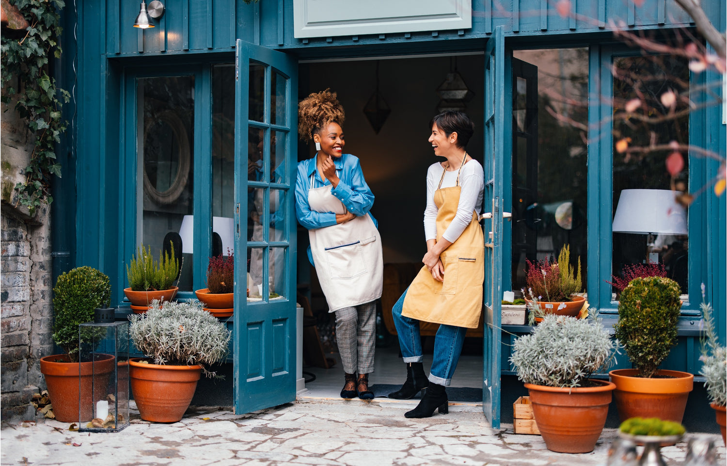 2 female business owners standing at the entrance of their store.