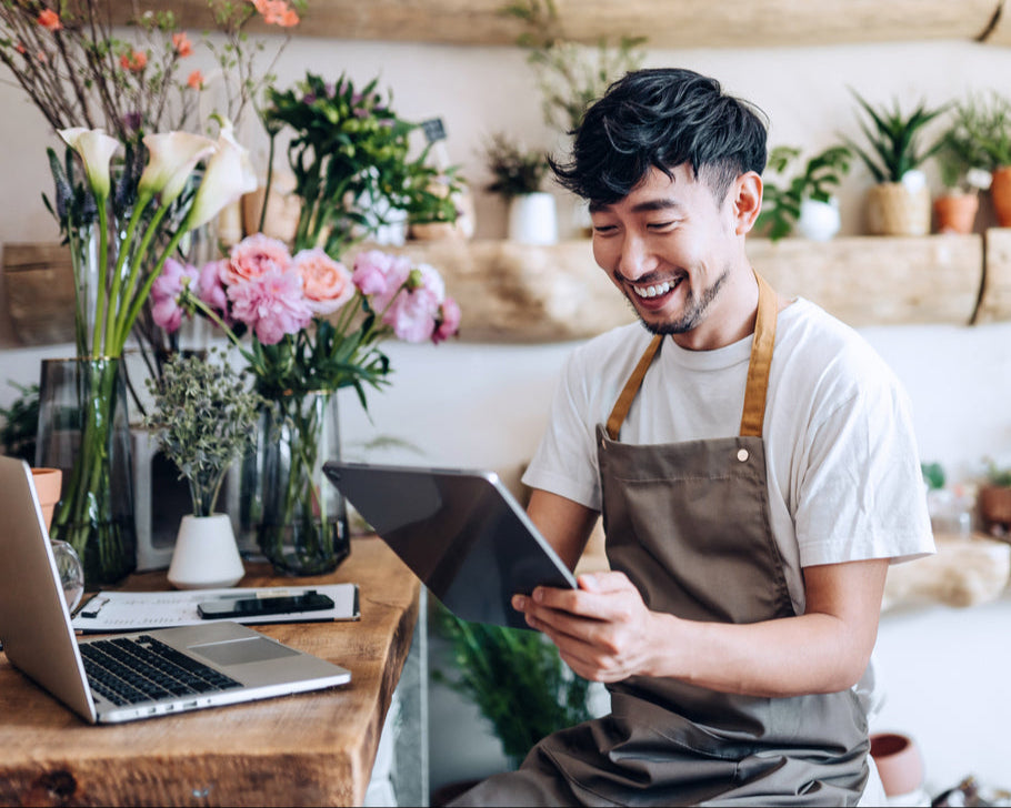 Male flower shop owner on laptop smiling